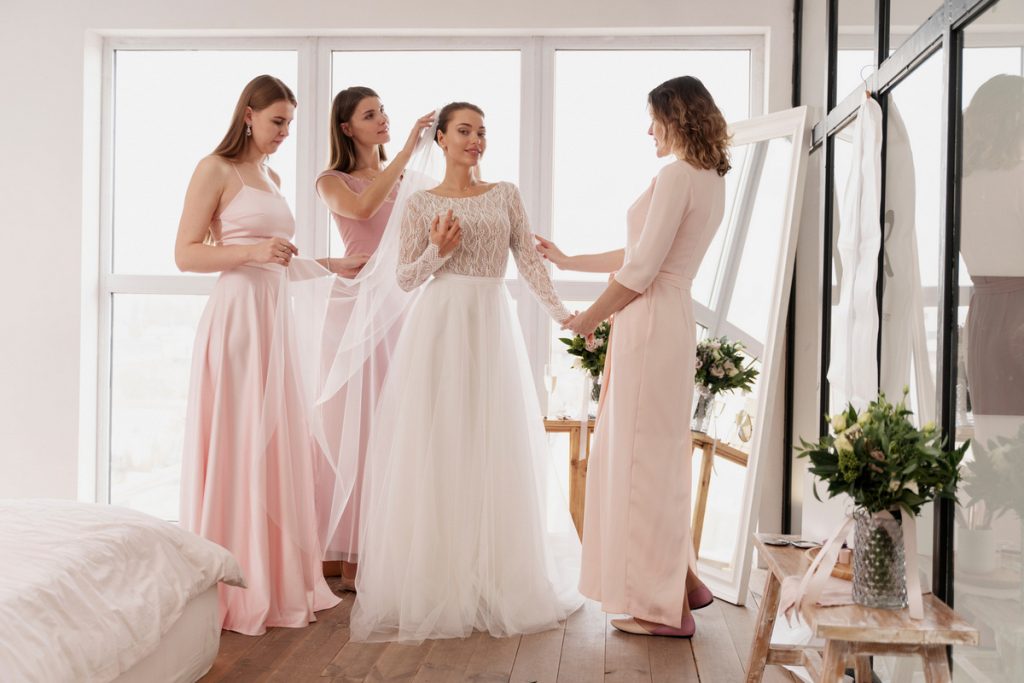 Bride with bridesmaids in soft pink chiffon bridesmaid dresses under 100 getting ready for the wedding day.