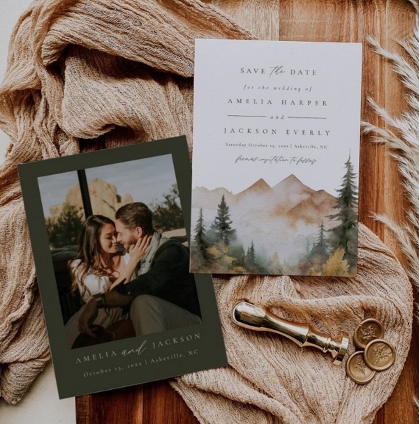 Rustic save the date cards with watercolor mountain design and engagement photo, styled with warm fabric and vintage details.