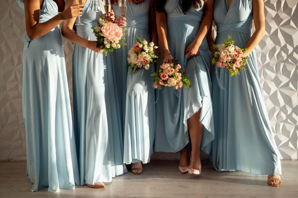 Bridesmaids wearing flowing turquoise bridesmaid dress holding pink and white floral bouquets.