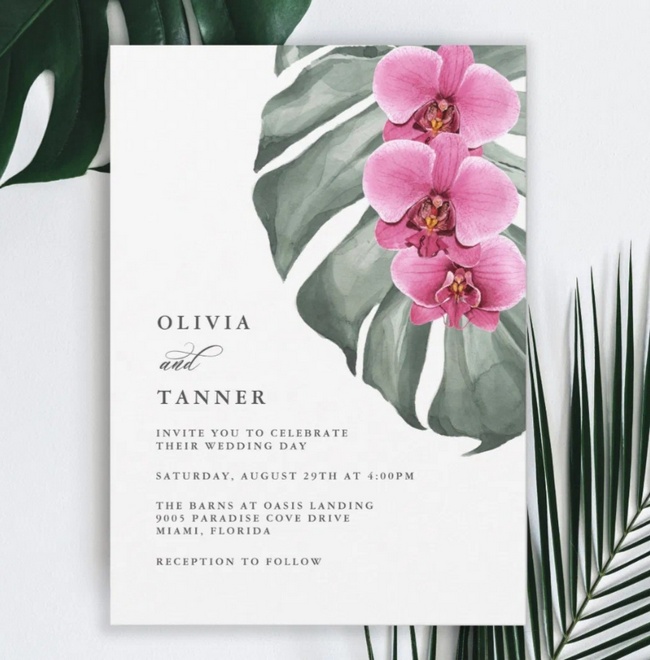 Tropical wedding invitation with hot pink orchids and green palm leaves.